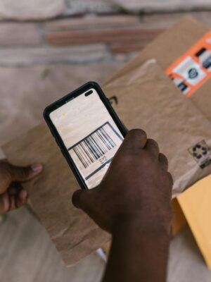 A person scans package barcodes using a smartphone for delivery logistics.