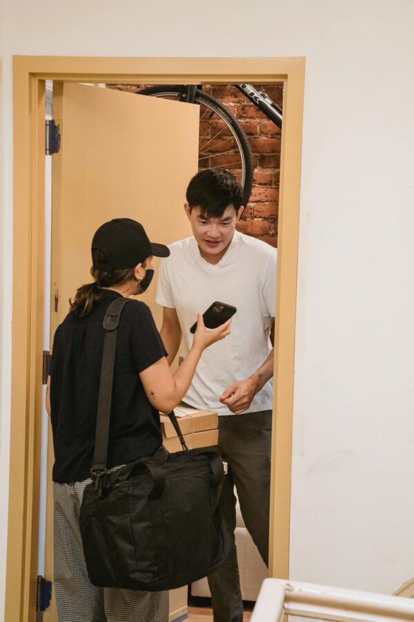 Delivery person handing over a package to a customer standing in his doorway.