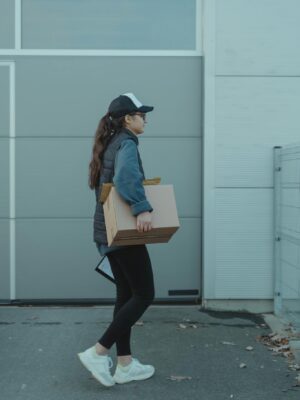 Woman courier carrying package outdoors, representing modern delivery services.