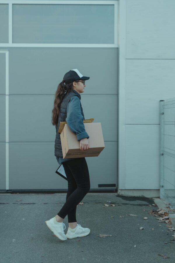 Woman courier carrying package outdoors, representing modern delivery services.